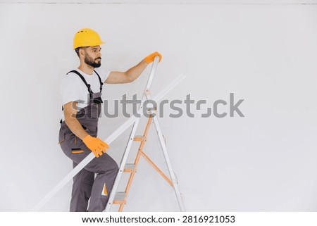 Worker installing molding on wall, renovating home, undertaking repairs, improving interior design, home improvement project