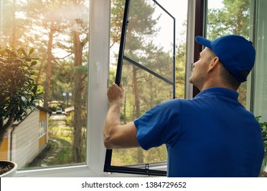 worker installing mosquito net wire screen on house window