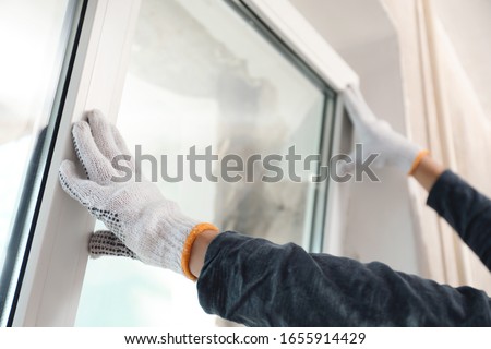 Worker installing plastic window indoors, closeup view