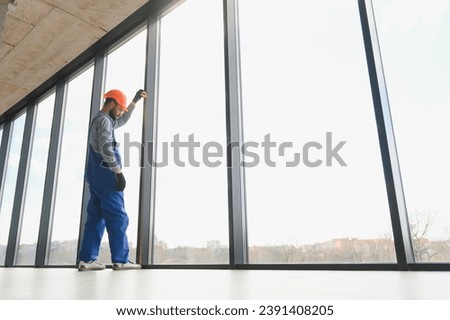 Worker installing plastic window indoors