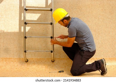  worker installing pool ladder in an empty swimming pool under construction