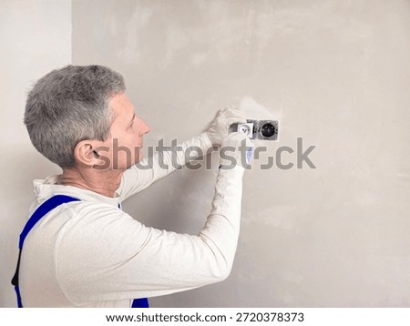 Worker installing the power outlet, close up. Socket box is installed on a concrete wall during rough repairs.