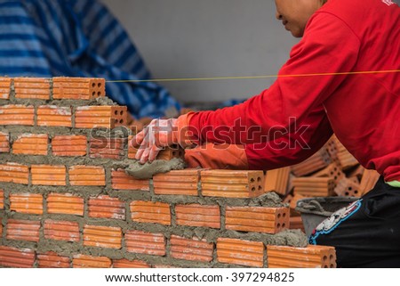 Worker installing red brick for construction site