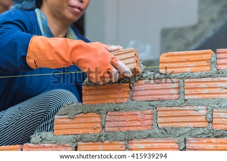 Worker installing red brick for construction site