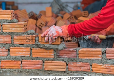 Worker installing red brick for construction site