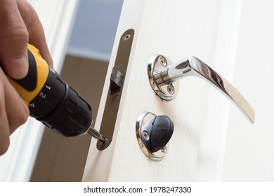 Worker Installing Or Repairing New Lock And Door Knob With Screwdriver. Locksmith Repair Or Install The Door Lock In House.