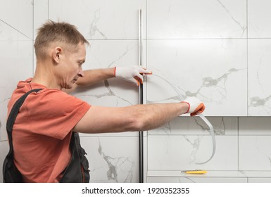 The Worker Is Installing A Silicone Gasket Seal In The Metal Profile Of The Shower Enclosure.