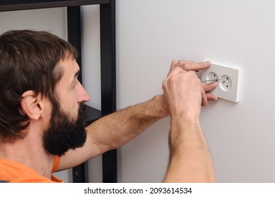 Worker installing socket in new house. Man installing light switch after home renovation. Electrician mounting electric sockets on the white wall. Electrician wiring a new build.