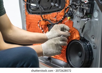 Worker installing special acoustic and vibration-damping material for noise insulation on car door. Soundproofing, auto tuning