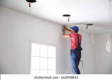Worker installing stretch ceiling in empty room. Space for text