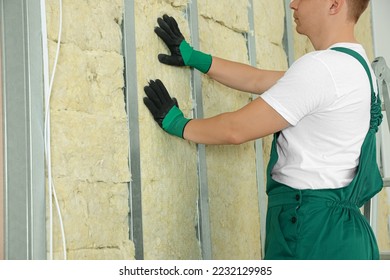 Worker installing thermal insulation material on wall indoors, closeup