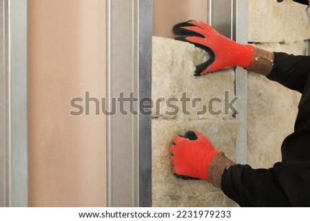 Worker installing thermal insulation material on wall, closeup