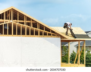 Worker installing underlayment sheet on wooden roof of new house. Renovation, improvement for exterior residential by professional builder. Durable build and construction business. Labor job concept - Shutterstock ID 2034707030
