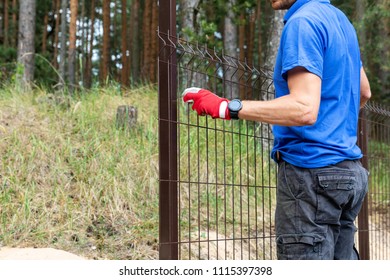 Worker Installing Welded Metal Mesh Fence