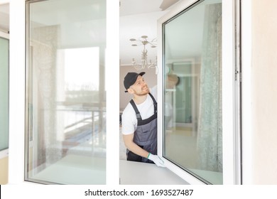 Worker in installing white plastic upvc window on house.
