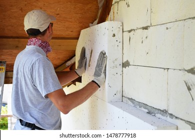 Worker Installing White Rigid Polyurethane Foam Sheet On Aerated Concrete Block Building Wall Facade For Energy Saving. Diy, House Improvement And Insulation Concept.
