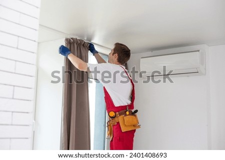 worker installing window curtain rod on the wall