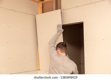 Worker installs drywall on the walls in the room.