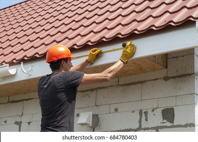 worker installs the gutter system on the roof