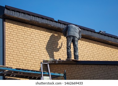 Worker installs plastic panels with bricks .