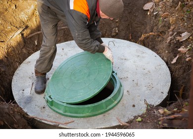 A Worker Installs A Sewer Manhole On A Septic Tank Made Of Concrete Rings. Construction Of Sewerage Networks For Country Houses.