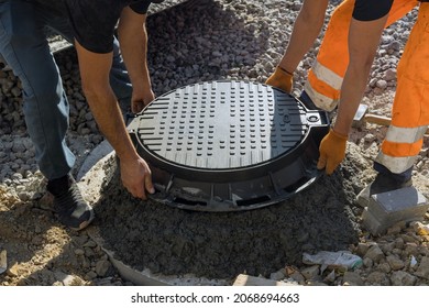 A worker installs a sewer manhole on a septic tank made of concrete rings with construction of sewerage