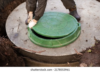 A Worker Installs A Sewer Manhole On A Septic Tank Made Of Concrete Rings. Construction Of Sewerage Networks For Country Houses.