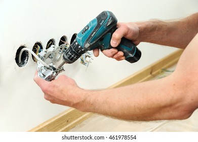 Worker installs a TV wall socket using a screwdriver.