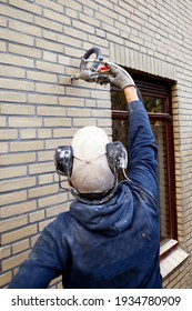 A worker insulating a house by injecting microbead pearls in the cavity walls 