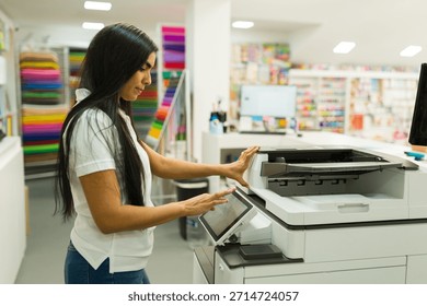 Worker interacting with a big copy machine, operating the touchscreen panel in a print shop or office supply store