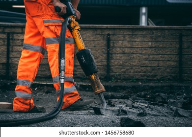 Worker Jack Hammering Out Broken Sections Of Asphalt Wearing Hi Vis Trousers 