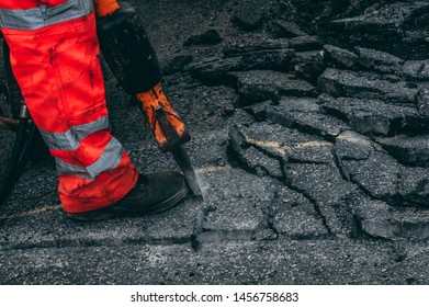 worker jack hammering out broken sections of asphalt wearing hi vis trousers 