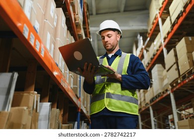 Worker with laptop computer in mail order warehouse.