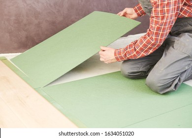 worker laying laminate floor underlayer padding - Shutterstock ID 1634051020