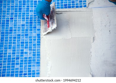 Worker laying tile in the pool. Pool repairing work. 