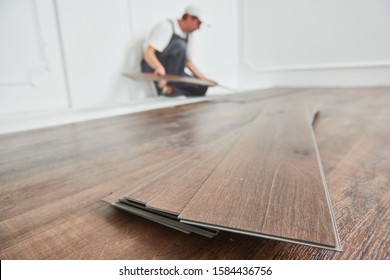 Arbeitskraft, die bei der Renovierung des Hauses den Vinyl-Fußbodenbelag legt