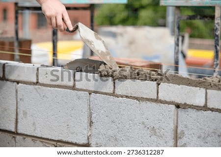 Worker lays bricks on a construction site while following guidelines for building walls