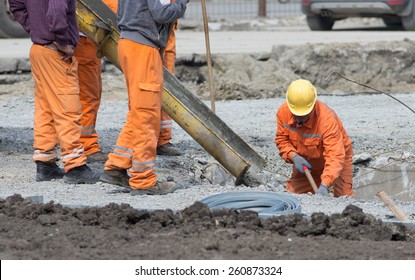 Worker leveling concrete poured from mixer on construction site