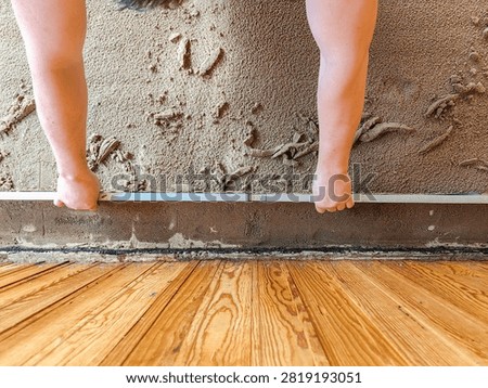 Worker leveling sand base with straightedge for tile flooring preparation for construction and renovation background