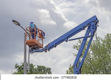 Worker In Lift Bucket During Installation Of Metal Pole With Street Lamp, Street Light Pole With Double Head.