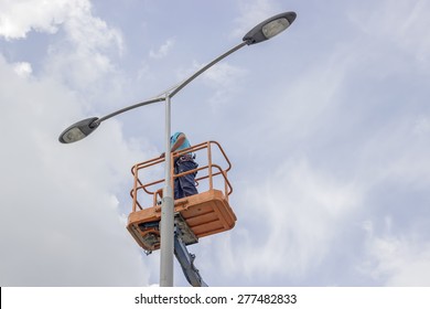 worker in lift bucket repair street light pole with double head