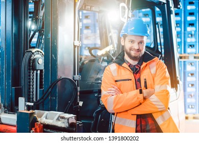 Worker In Logistics Distribution Center Leaning Against His Forklift