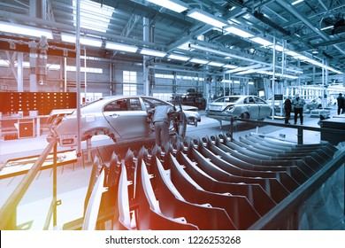 Worker looks into car body on production line. Factory for production of cars in blue. Modern automotive industry. Blue tone
