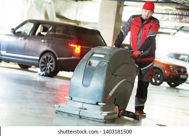 Worker With Machine Cleaning Floor In Parking Garage.