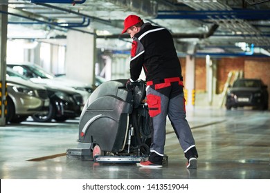 Worker With Machine Cleaning Floor In Parking Garage.