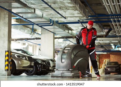 Worker With Machine Cleaning Floor In Parking Garage.