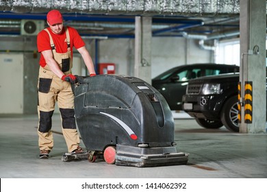 Worker With Machine Cleaning Floor In Parking Garage.