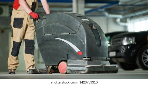 Worker With Machine Cleaning Floor In Parking Garage.