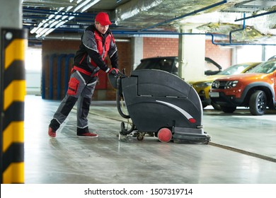 Worker With Machine Cleaning Floor In Parking Garage.