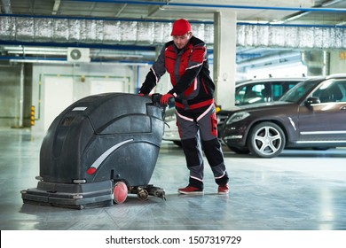 Worker With Machine Cleaning Floor In Parking Garage.